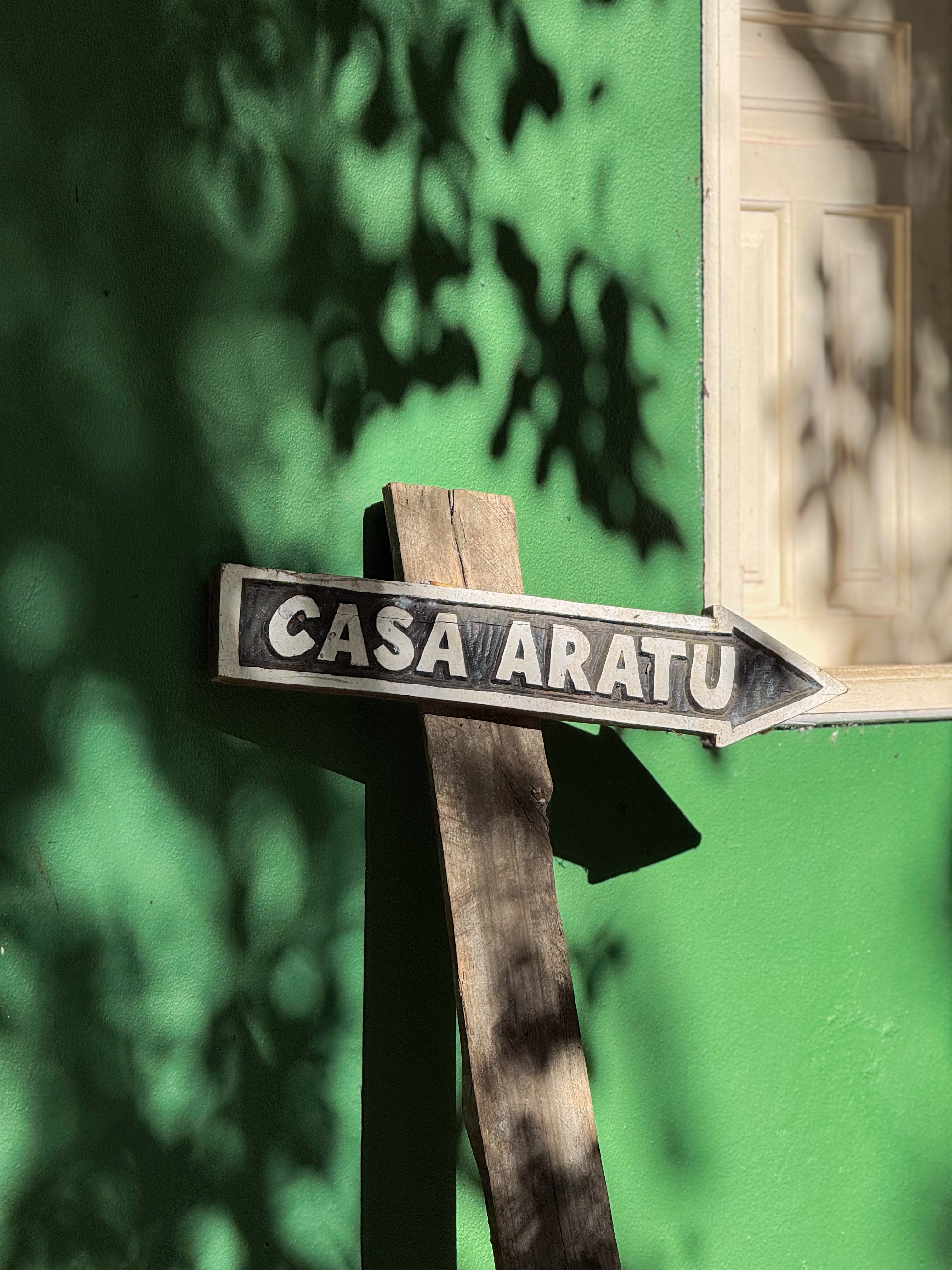 Placa Pousada Aratu na parede verde