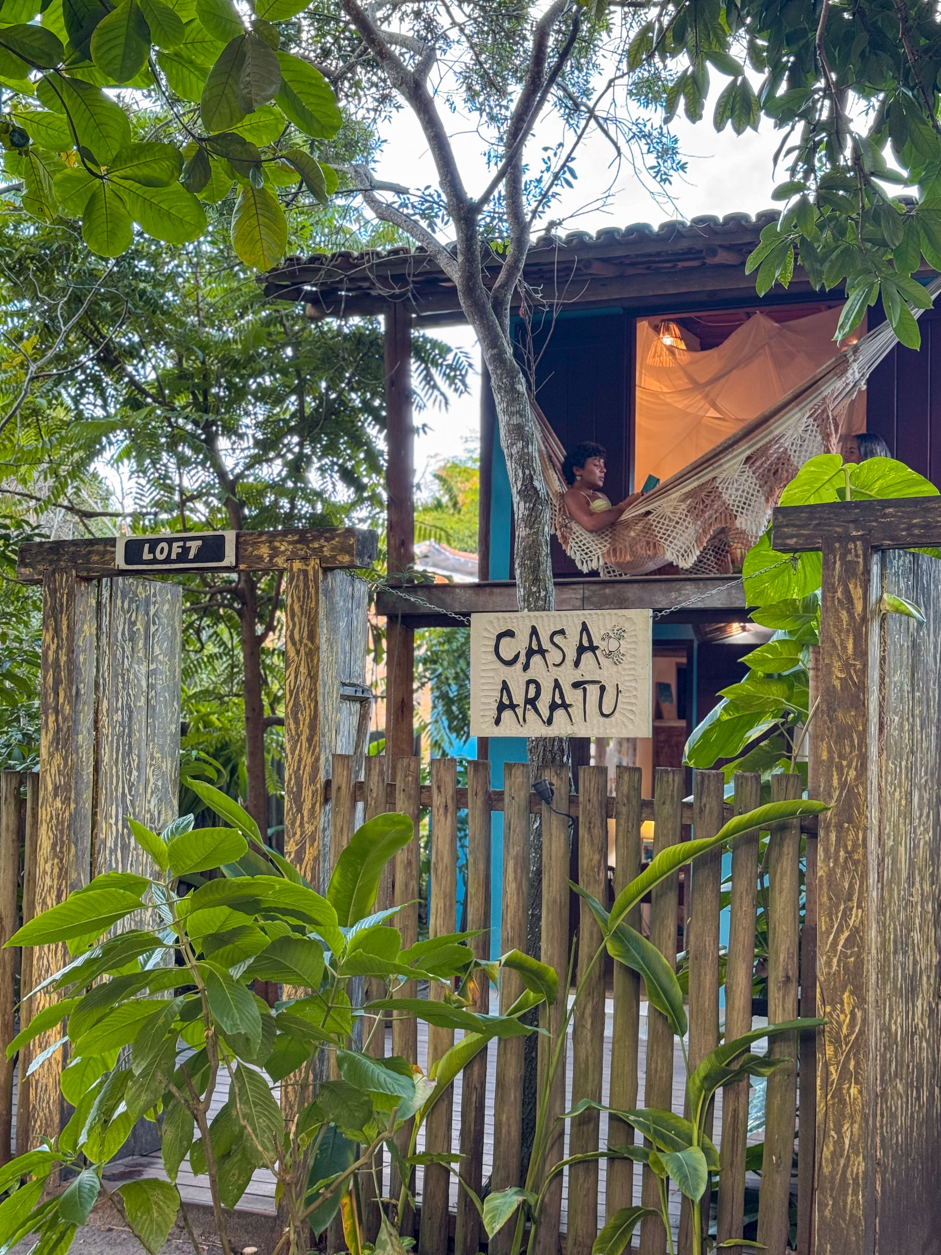 Entrada da Pousada Aratu — loft com rede entre as árvores