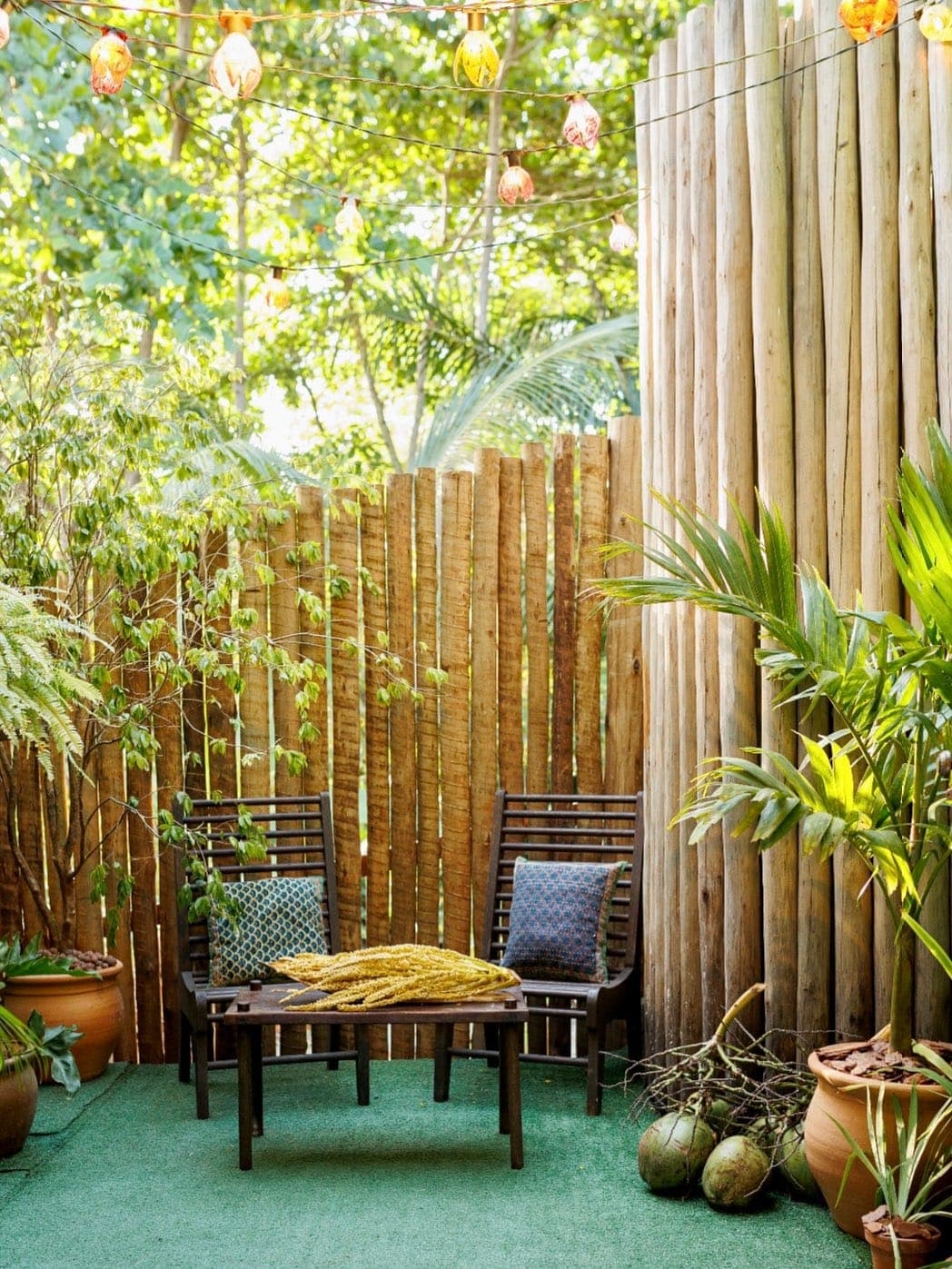Quintal com cadeiras de madeira, plantas tropicais e luzes coloridas — atmosfera de Caraíva